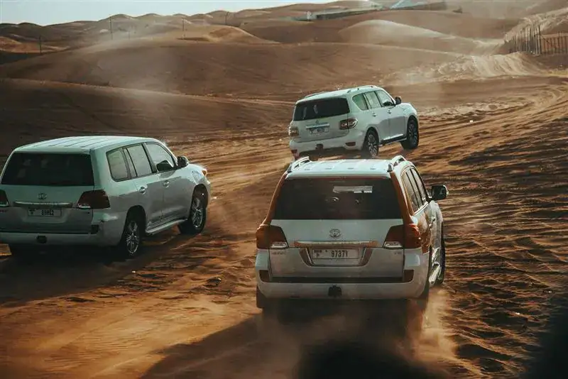 Off-road SUVs navigating desert terrain in the sandy dunes.